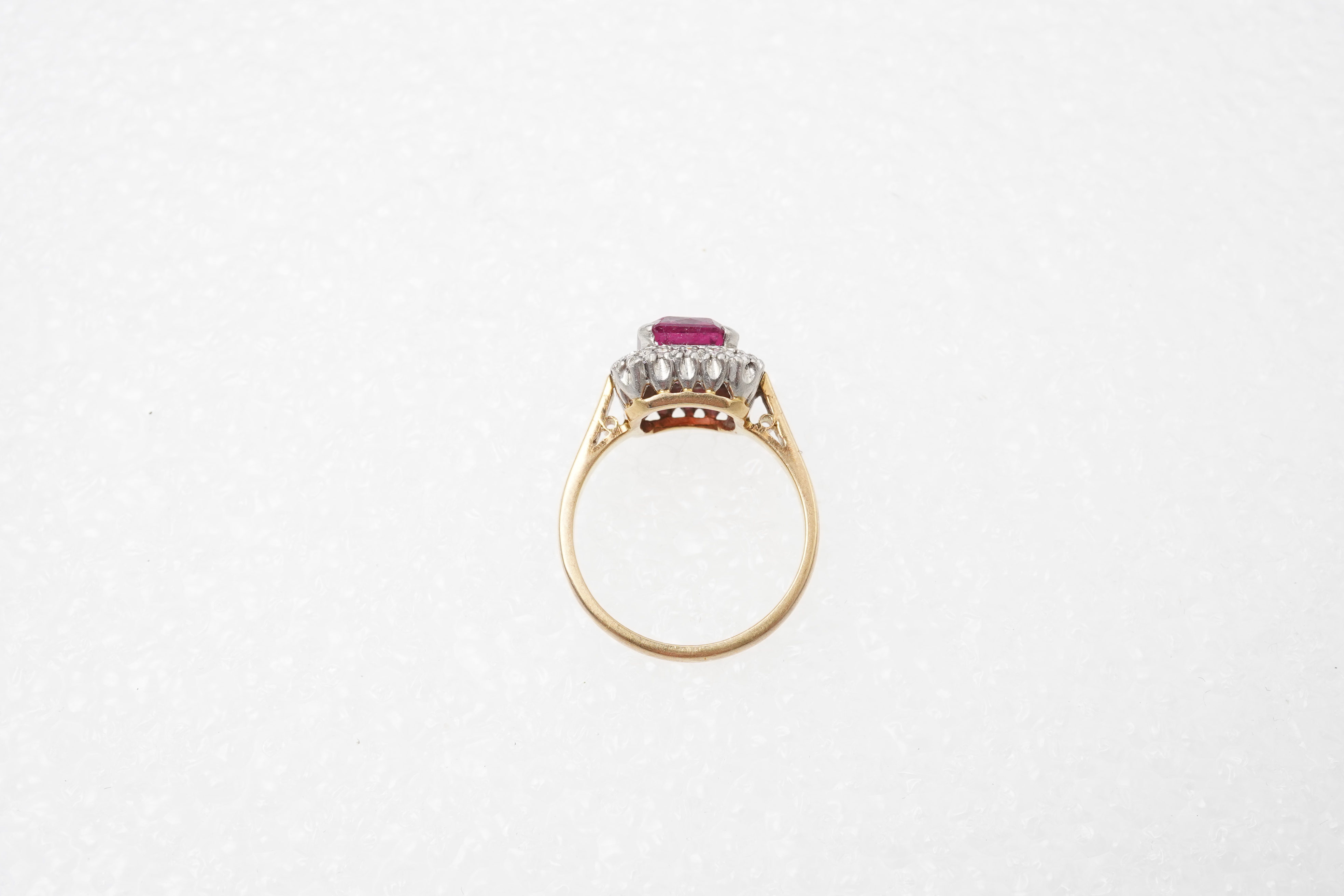 A pink tourmaline and diamond ring, claw-set with a mixed-cut pink tourmaline measuring approximately 8.5 x 7.4 x 4.3mm, within a border of single-cut diamonds totalling approximately 0.20 carats, mounted in gold and pla